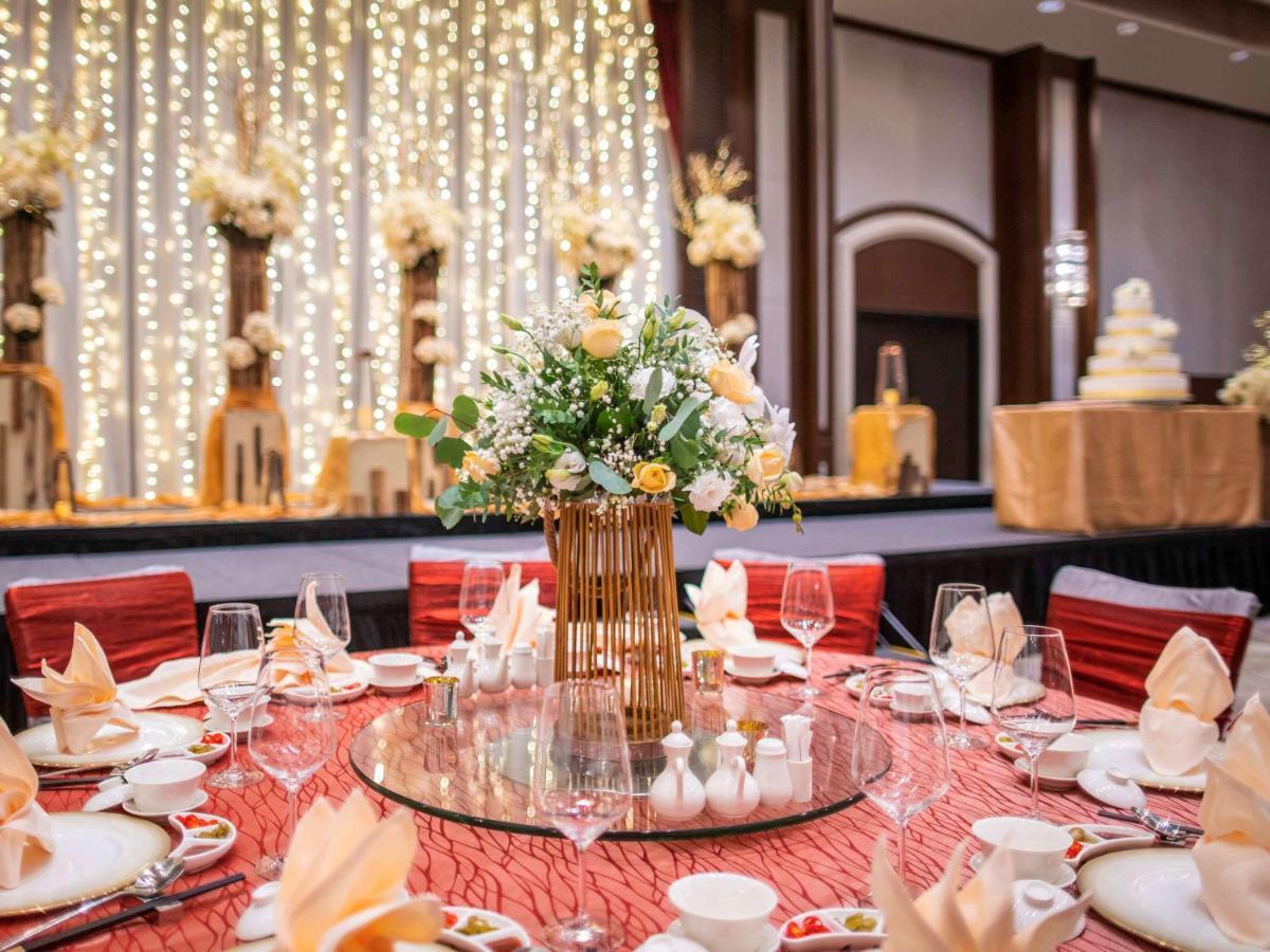 Paradox Singapore Merchant Court At Clarke Quay Екстер'єр фото The photo depicts an elegantly arranged dining setup for a formal event. In the foreground, there is a round table covered with a textured red tablecloth. The table is adorned with various dining ware, including plates, cups, wine glasses, and beauti